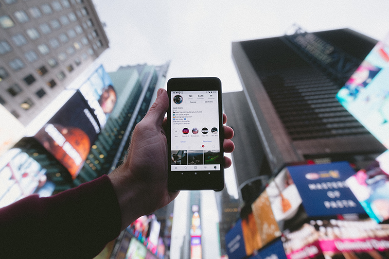 Person holding mobile phone with instagram apps on the screen