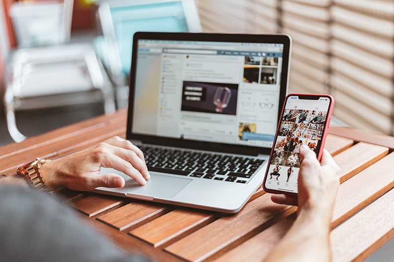 a person holding a cellphone and laptop on the table