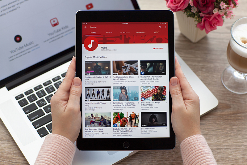 Woman holding a iPad Pro Space Gray with video sharing website YouTube on the screen