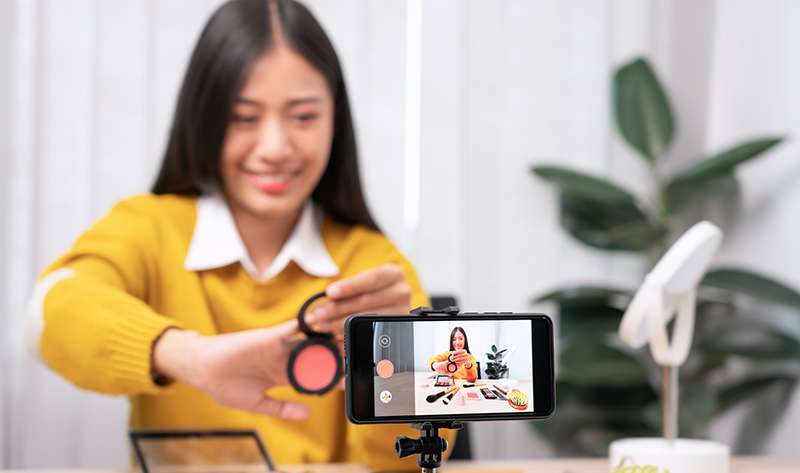 Beautiful asian woman blogger using camera phone for recording video