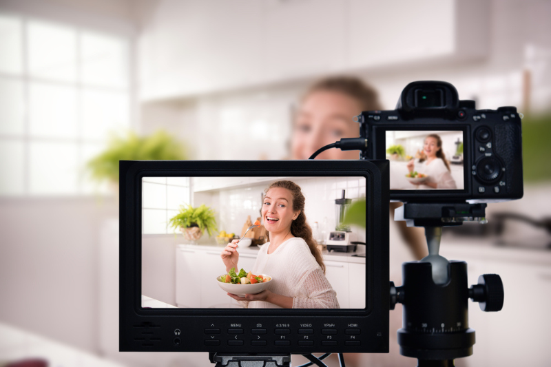 Young female blogger vlogger in front of video camera