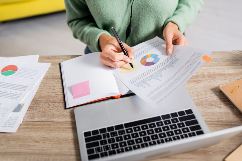 Cropped woman holding pen and paper with chart analytics