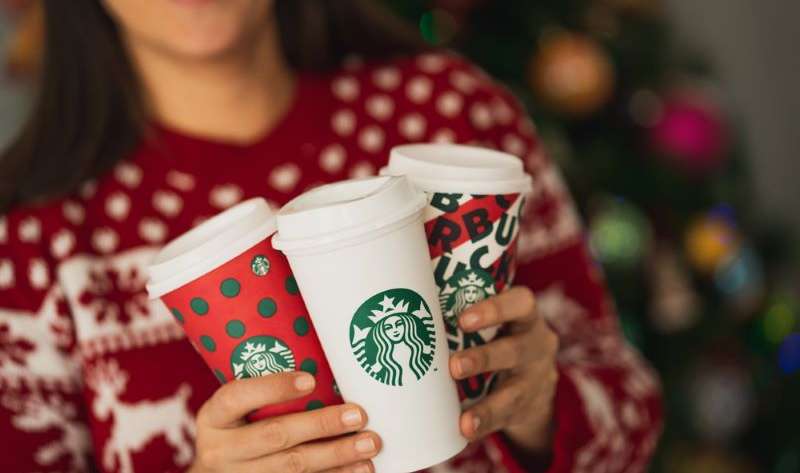 Happy woman holding three tall starbucks cup