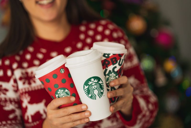 Happy woman holding three tall starbucks cup