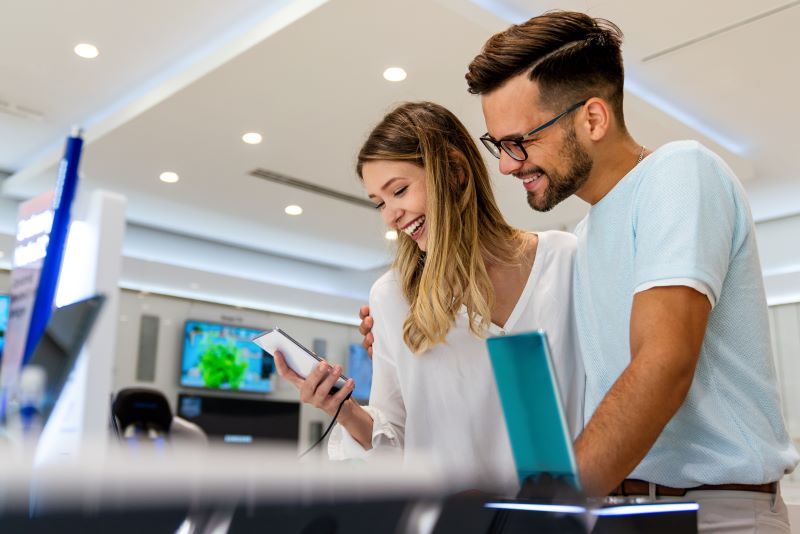 Happy young people shopping new mobile phone in a store. 