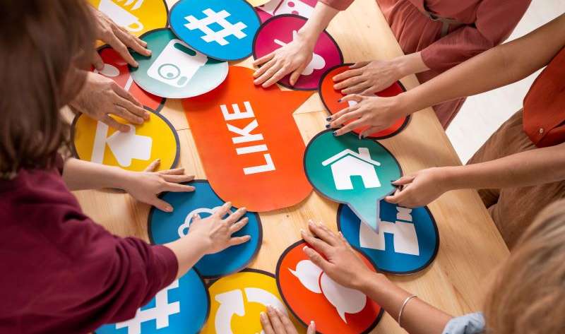 Hands of several friendly millennials choosing paper speech bubbles with social media icons