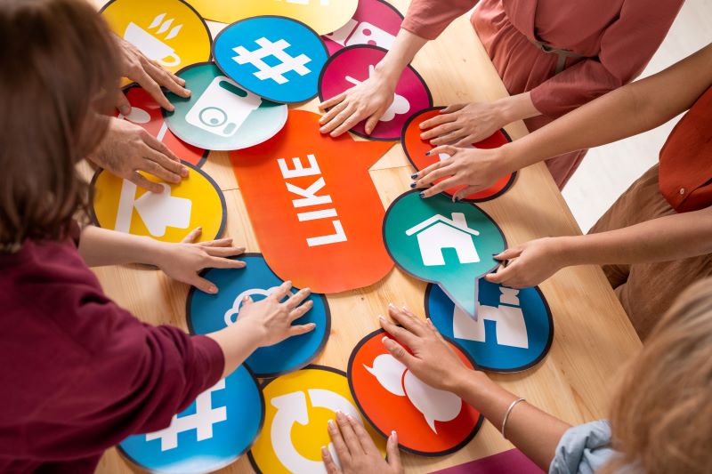 Hands of several friendly millennials choosing paper speech bubbles with social media icons