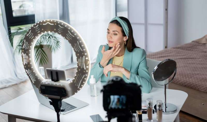 Influencer beauty blogger applying face foam near devices and ring lamp